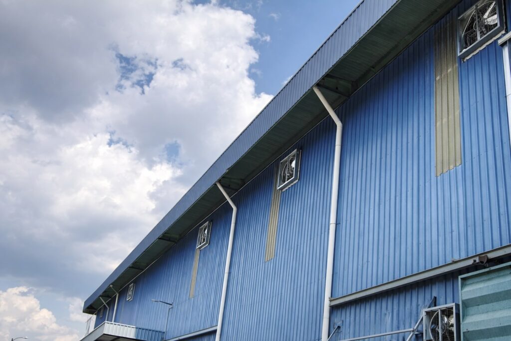 External view of a blue industrial factory featuring multiple CrystalAir box-type exhaust fans installed for active ventilation.