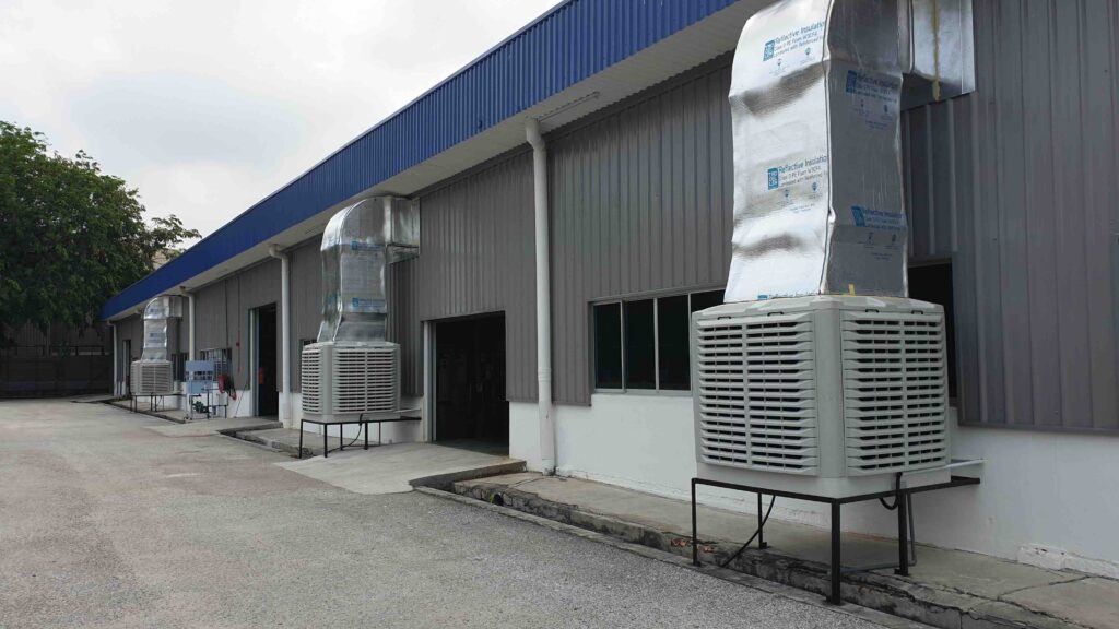 Multiple industrial top-discharge air coolers installed outside factory building with vertical ducting system in Malaysia