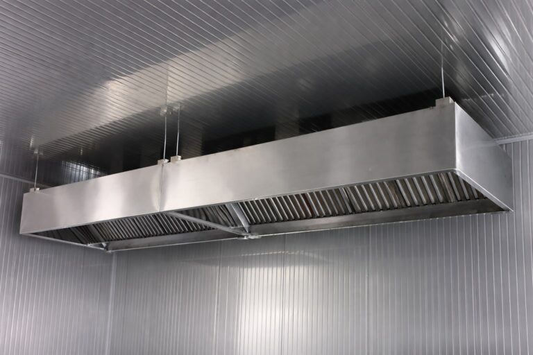 Stainless steel industrial kitchen exhaust hood with grease baffle filters installed for commercial ventilation