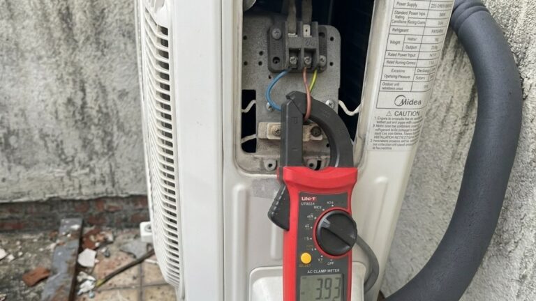 technician measuring air conditioner running current using clamp meter during servicing in Malaysia