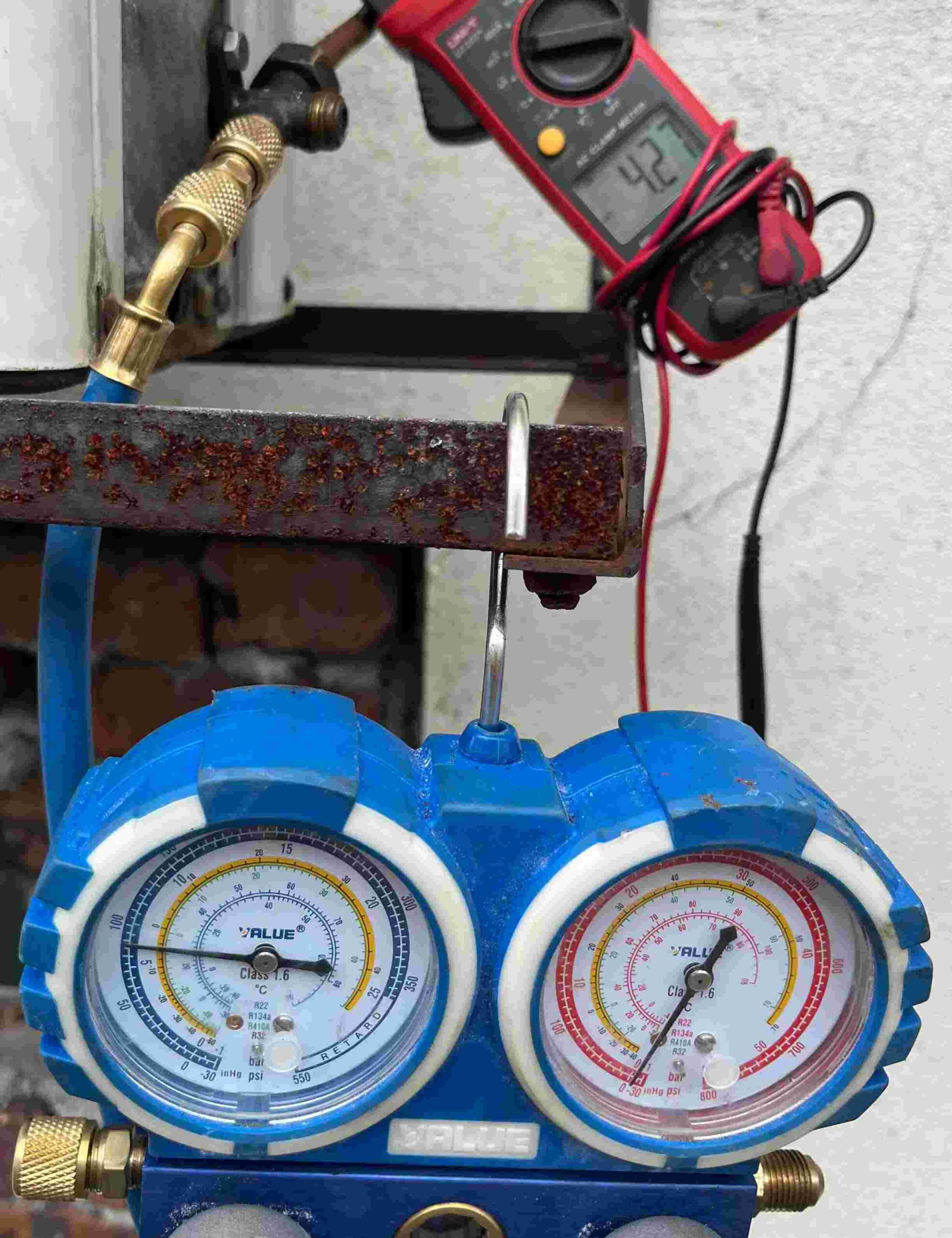 Technician checking air conditioner refrigerant pressure using manifold gauge in Malaysia