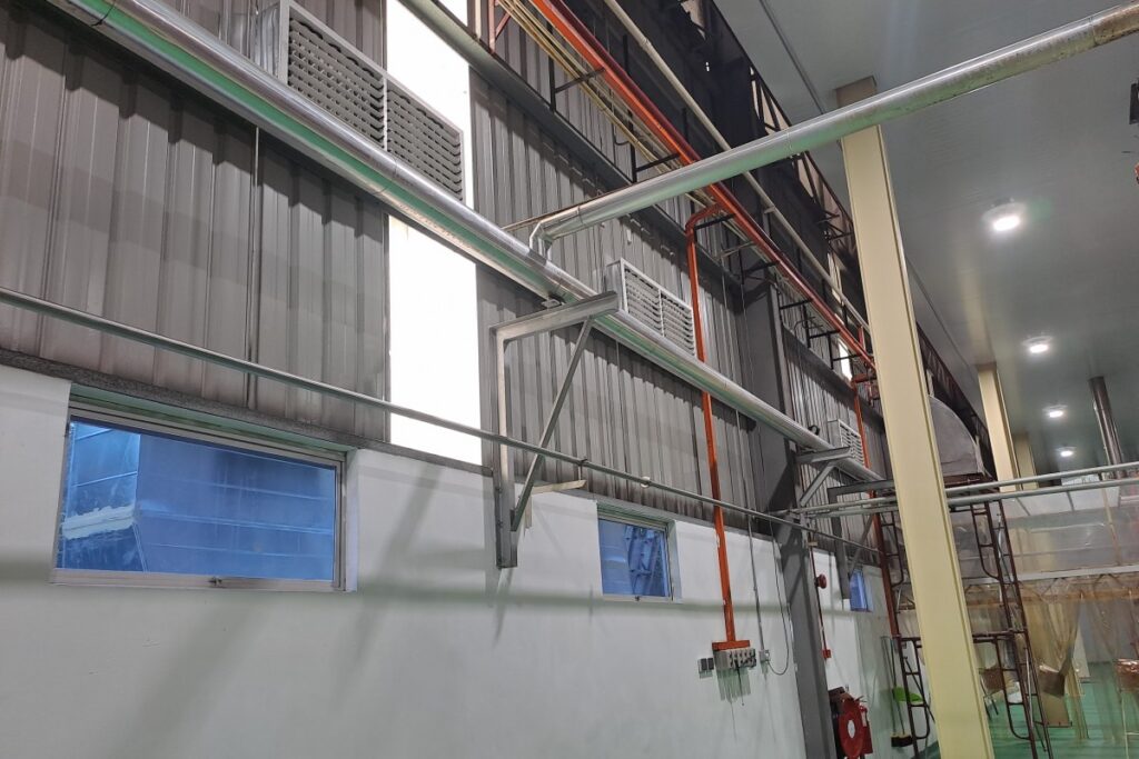 Ducting and air outlets installed for evaporative air cooler supply inside an instant noodle factory production floor.