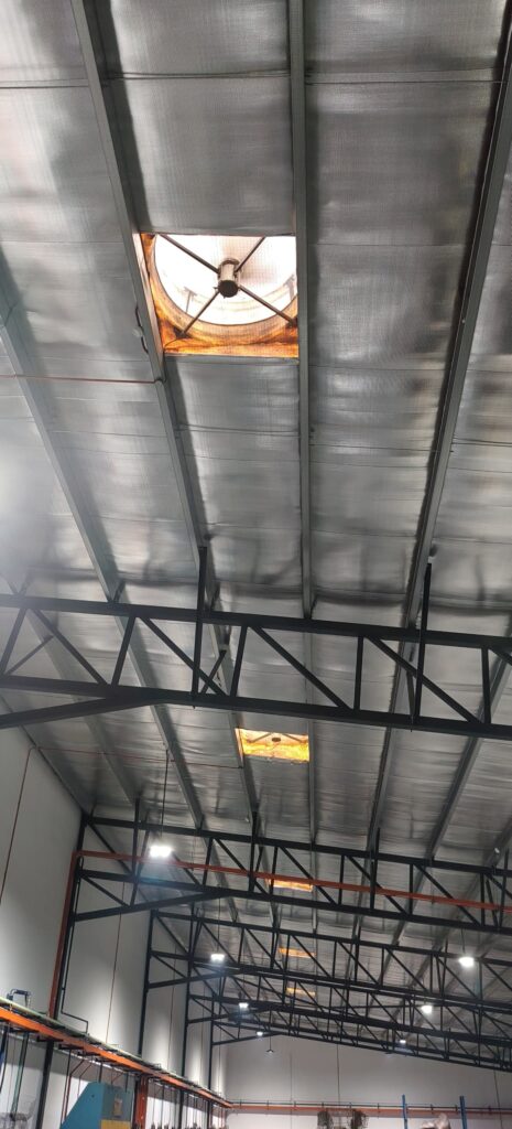 Interior view of rooftop exhaust fan openings installed above a metal fabrication factory for high-level hot air extraction.