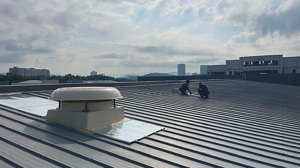 Rooftop exhaust fan installation in progress on the roof of a metal fabrication factory.
