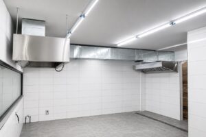 Restaurant kitchen exhaust hood system with two hoods and ducting connected for rooftop discharge.