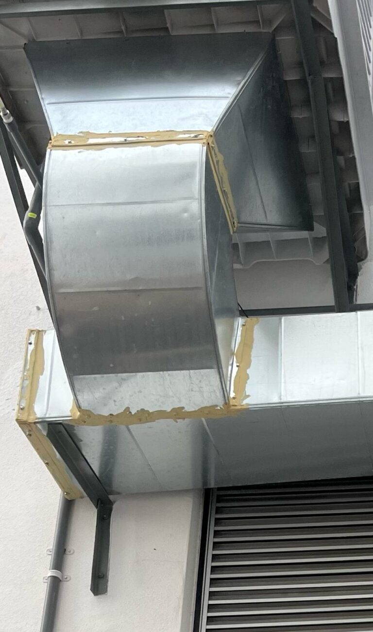 Restrictive ducting arrangement connected directly below an industrial evaporative air cooler.