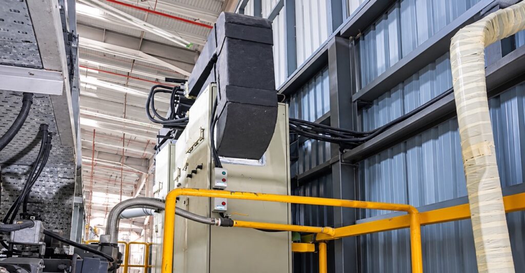 Ducted air conditioner installation in a cramped and hot industrial machine area.