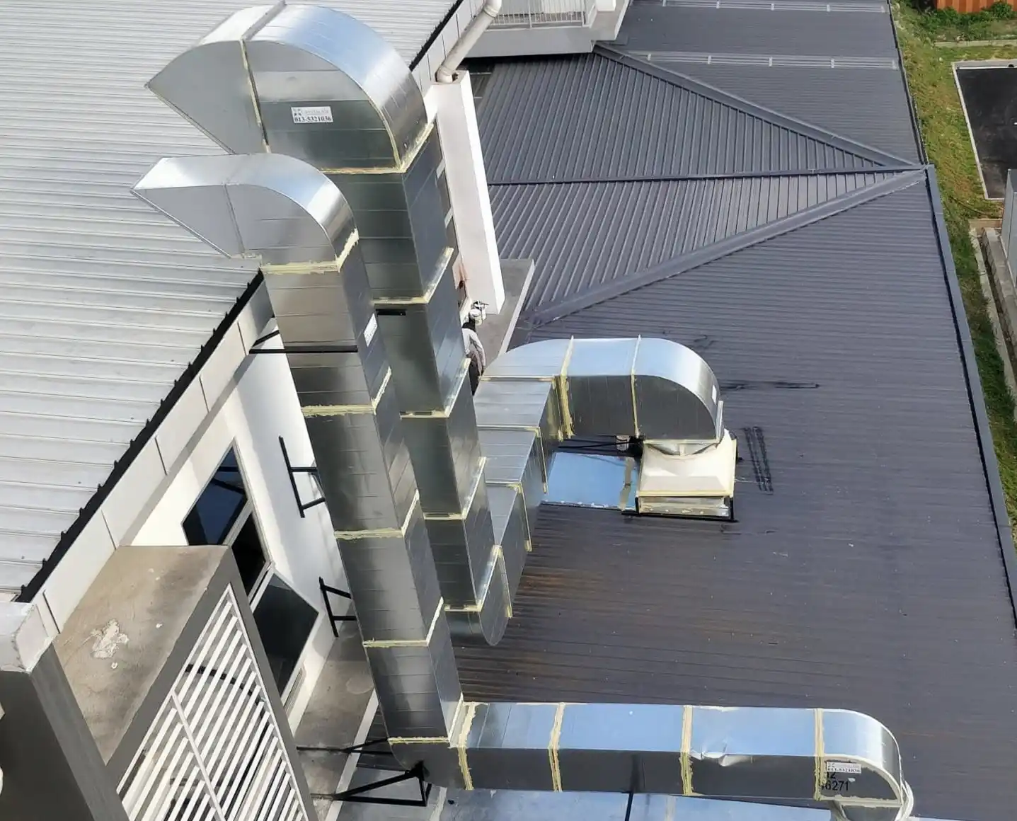 Exterior industrial ventilation ducting installation with weatherproof roof penetration for factory building in Malaysia