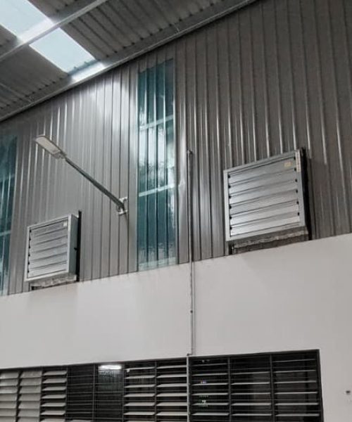 Box type exhaust fans installed on the zinc wall of a metal fabrication factory for ground floor air extraction.
