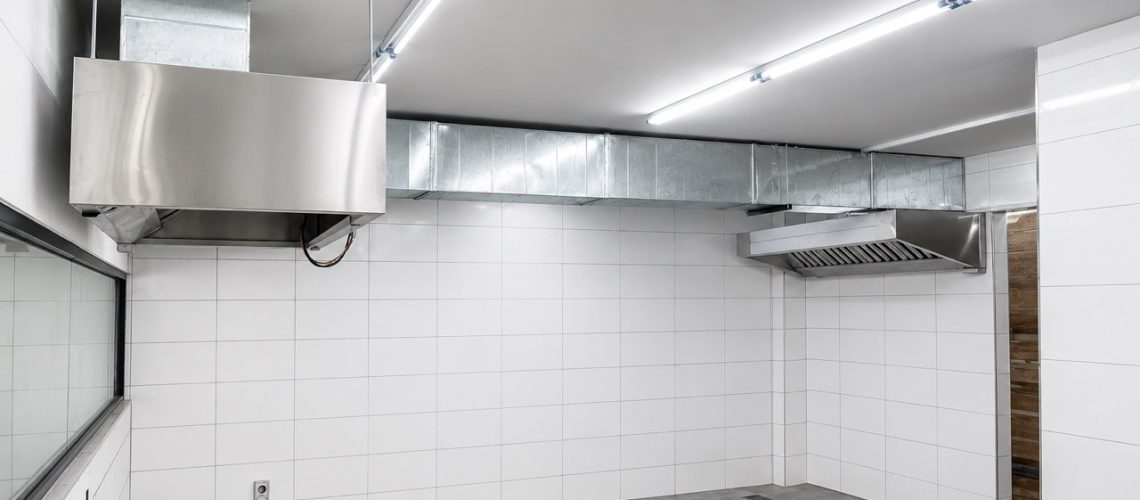 Restaurant kitchen exhaust hood system with two hoods and ducting connected for rooftop discharge.